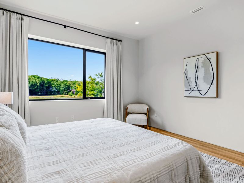 King Bedroom 6 - A large window frames the forest beside the king bed.