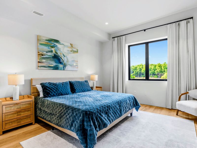 King Bedroom 5 - A window with a lake view and a sitting chair beside the king bed.