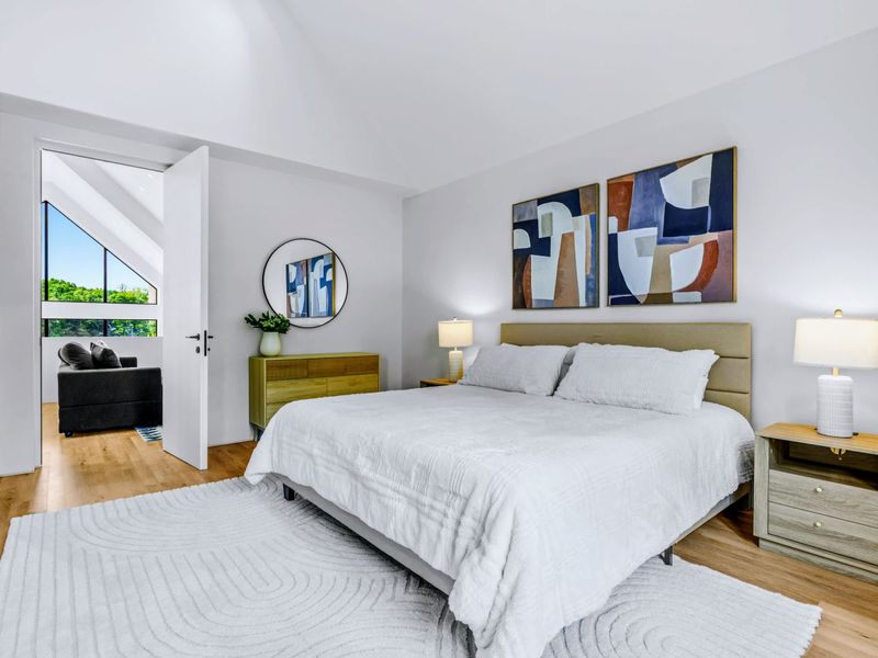 Upstairs King Suite - A king bed framed by bold, colorful art under the vaulted ceiling.
