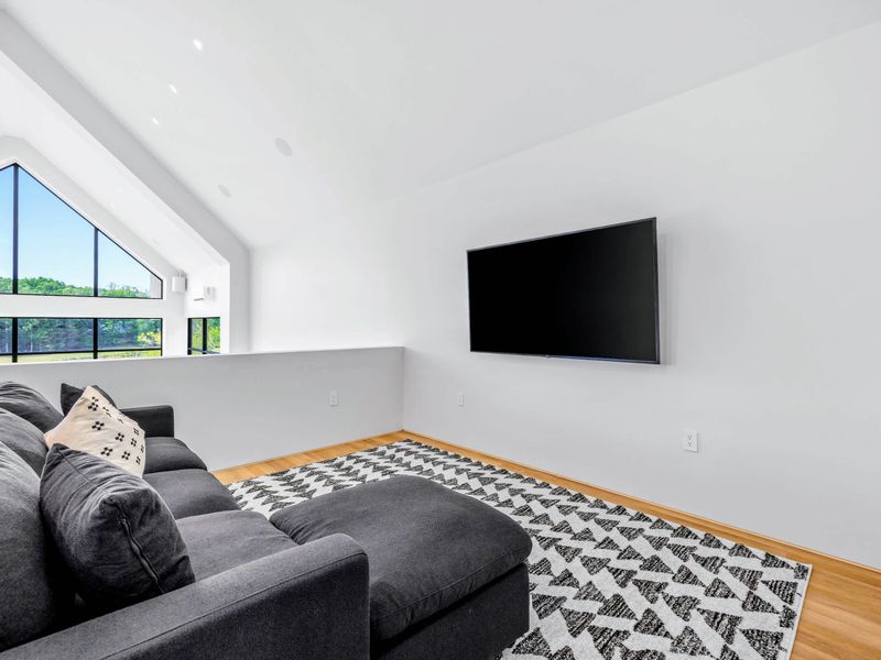 Loft Lounge - An upper-level sitting room with a sectional and mounted TV under the vaulted peak.