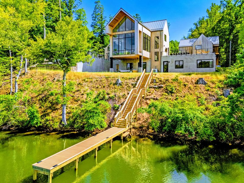 Aerial View - The property in context, forest meeting calm lake water.