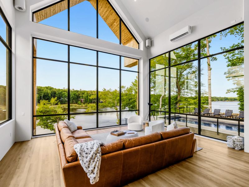Great Room - A leather sectional under soaring A-frame glass, the lake beyond the trees.