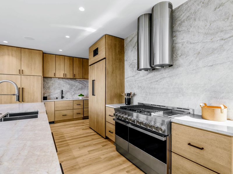 Chef's Kitchen - Stainless range and hood set against stone and warm wood.
