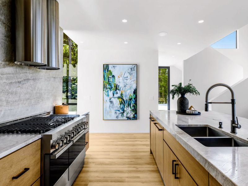 Chef's Kitchen - The gas range and main sink, open to the living area and its glass walls.