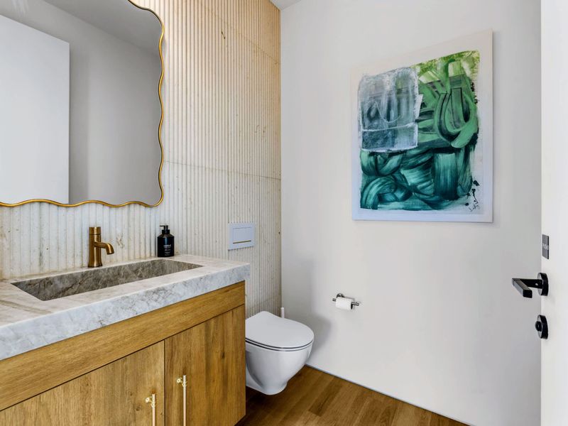 Powder Room - A sculptural mirror and vessel sink in the main-level half bath.