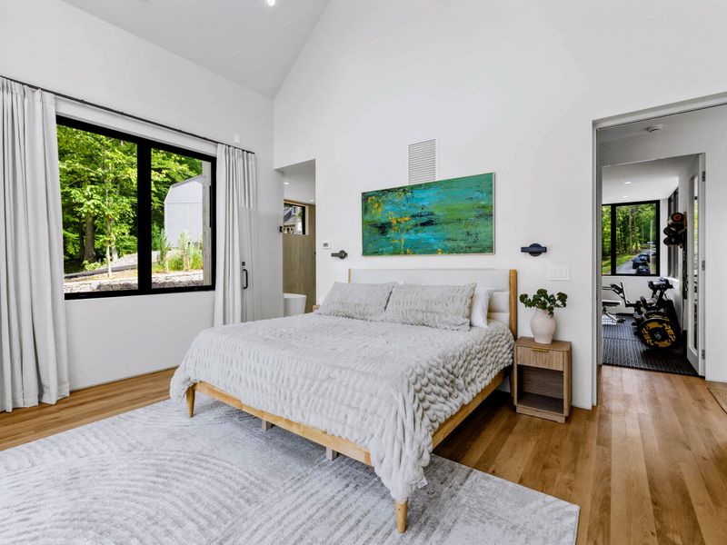 Primary Suite - Wide windows and a sitting area fill the room with forest light.