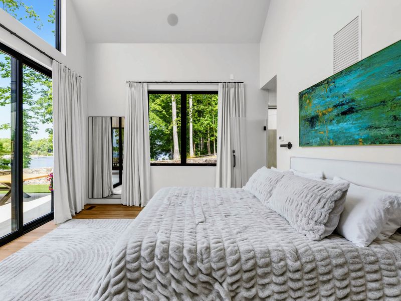 Primary Suite - French doors open to the deck and trees from the main-level retreat.