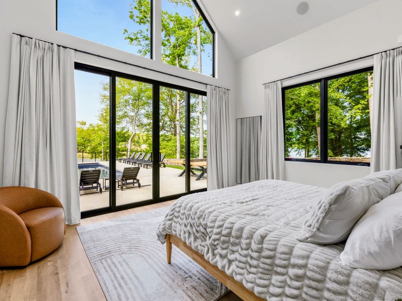 Primary Suite - Floor-to-ceiling glass and a leather lounge chair, the lake just outside.