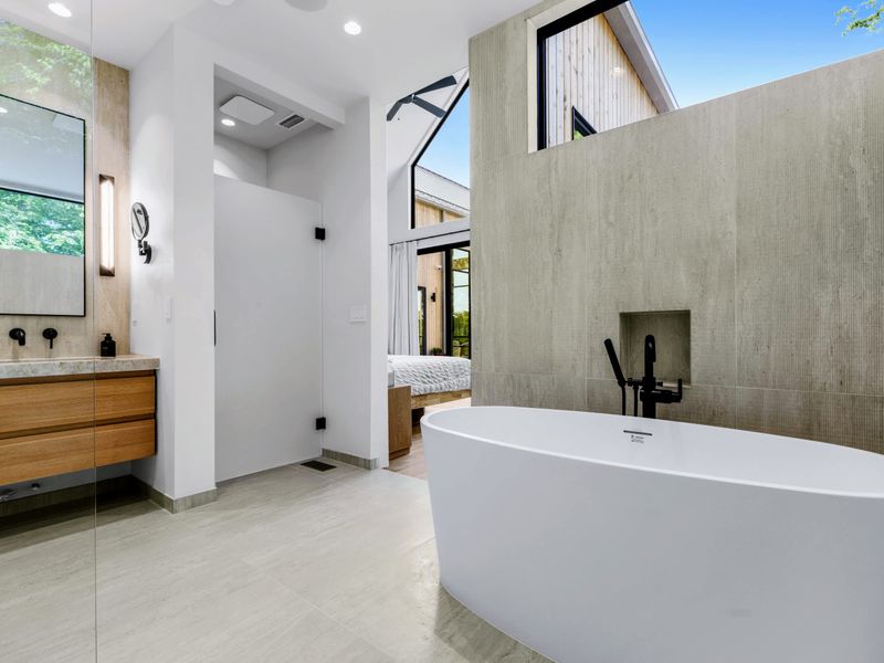 Primary Bath - Soaking tub and a wood double vanity under soft natural light.