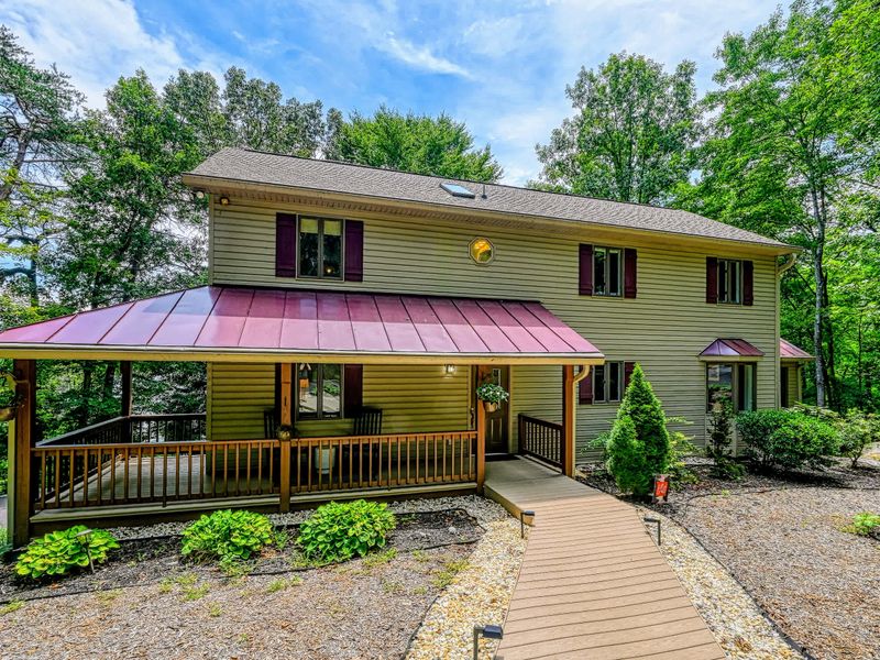 Welcome to Avoca Cove - A welcoming facade with a covered, rocking-chair front porch under a striking red metal roof.