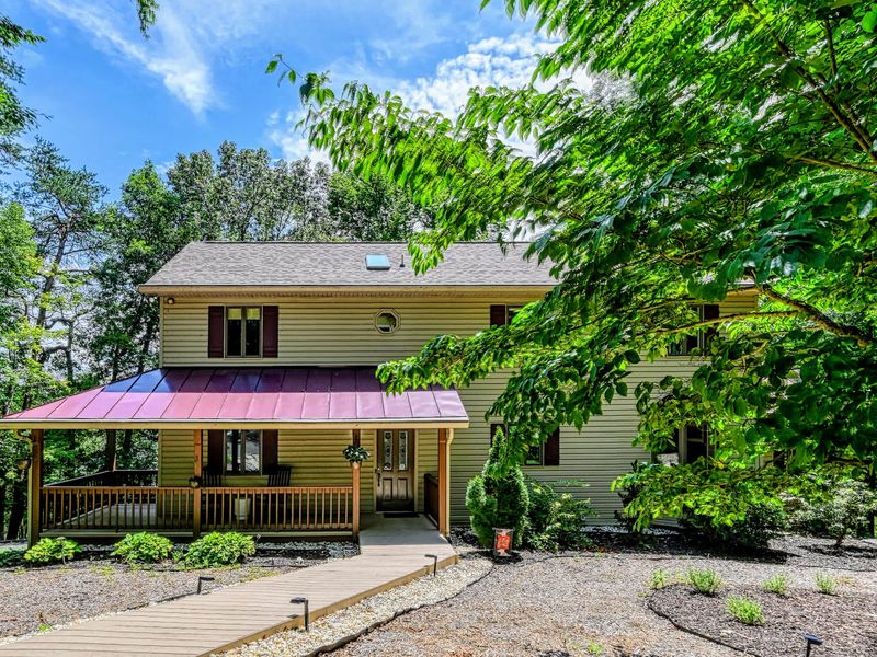 Curb Appeal - Tucked into mature trees with tidy landscaping and a wood walkway up to the covered porch.