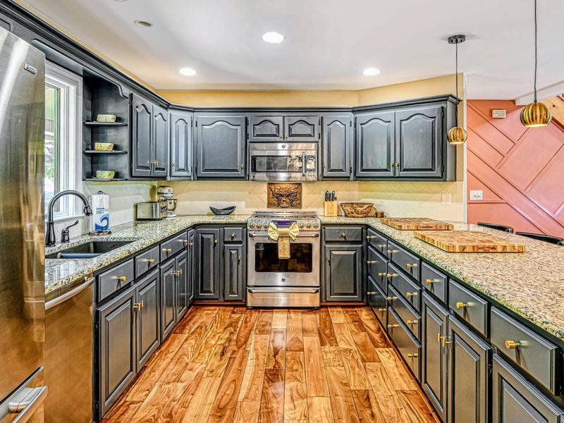Kitchen - Gray cabinets, granite counters, and stainless appliances open straight to the great room.