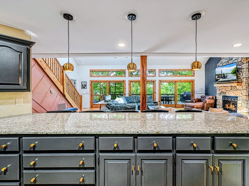 Breakfast Bar - The granite peninsula opens to the great room, fireplace, and wall of windows, the cook always part of the action.