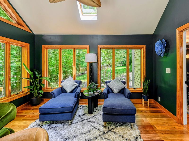 Garden Room - Deep green walls and wraparound windows blur the line between inside and the woods outside.