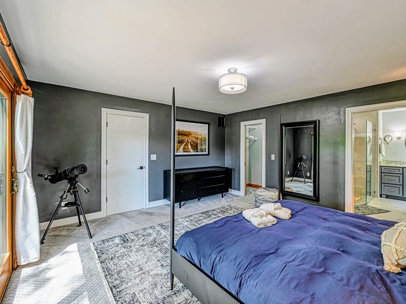 Primary Suite - A king bed with a telescope at the window for stargazing and the ensuite bath just steps away.