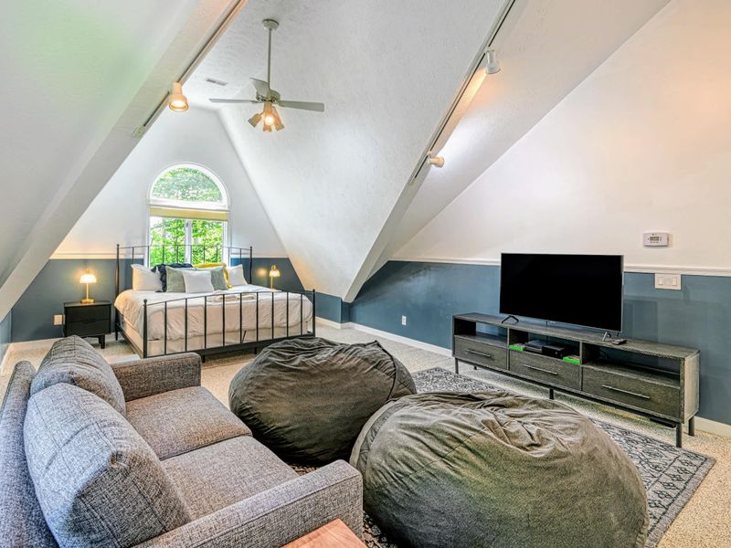 Bonus Bedroom - A king bed under an arched window, plus a sofa, bean bags, and a smart TV, the upstairs hangout kids claim first.