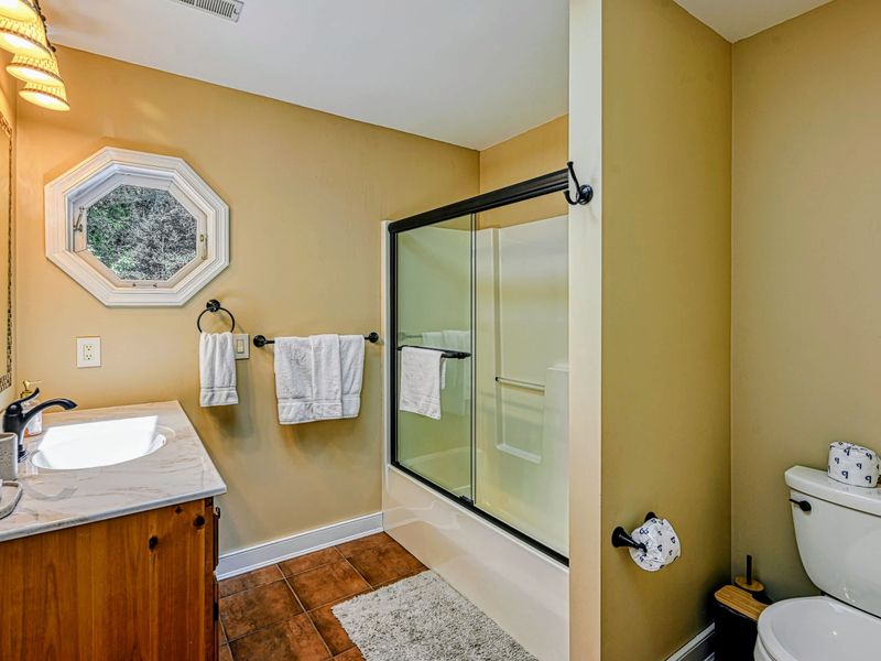 Bathroom 2 - A full hall bath with a glass-enclosed tub and shower and a granite-topped wood vanity.