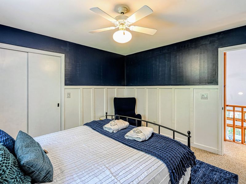 Bedroom 2 - A queen bed against a navy accent wall with board-and-batten trim and a ceiling fan.