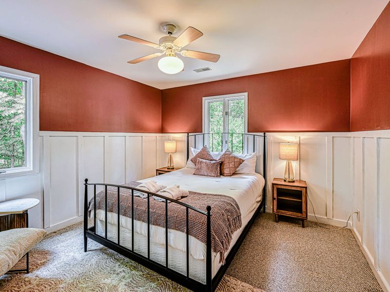 Bedroom 3 - A queen bed framed by a warm terracotta accent wall and white wainscoting.