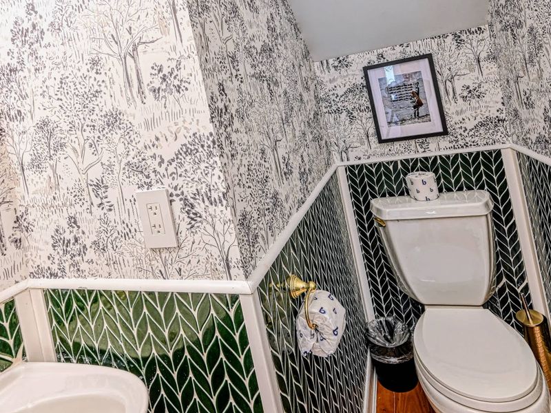 Powder Room - A charming main-level half bath with whimsical forest wallpaper and emerald herringbone tile.