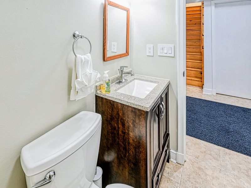 Bath Detail - A framed mirror and warm wood vanity finish the lower-level bath, steps from the living room.