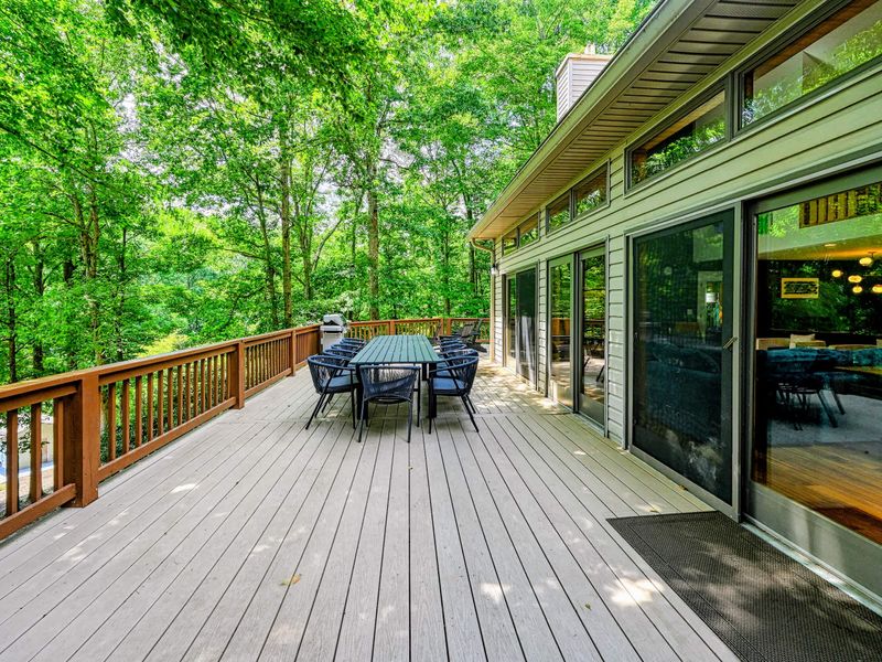 Back Deck - The deck runs the length of the home with sliding doors to the dining and living areas, the lake just through the trees.