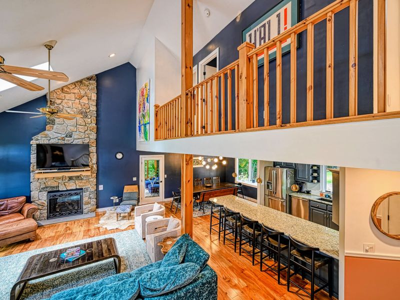 Main Level Flow - Living, dining, and kitchen share one bright, open footprint beneath the loft, the stone fireplace anchoring it all.