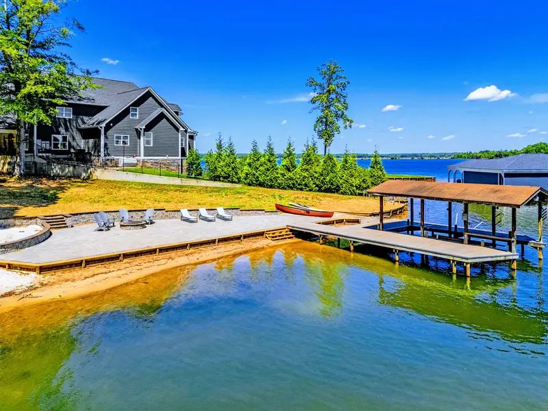 Aerial View - The A-frame retreat on 1.5 wooded acres, the lake wrapping the property's edge.