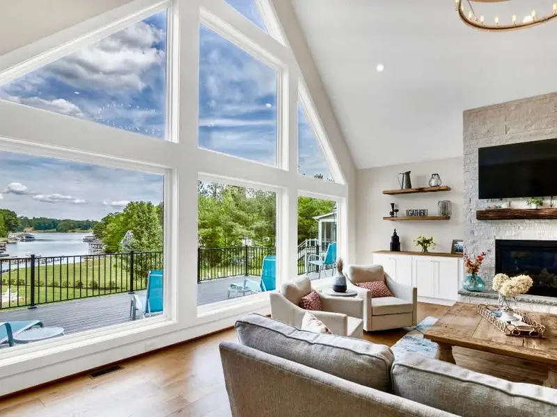 Great Room - Our two story vaulted ceilings & wall of windows fill the living room with natural light, anchored by our white stone fireplace & live edge rustic mantle with wood from an 1800's log cabin! So many authentic antiques fill Blueberry Bay!