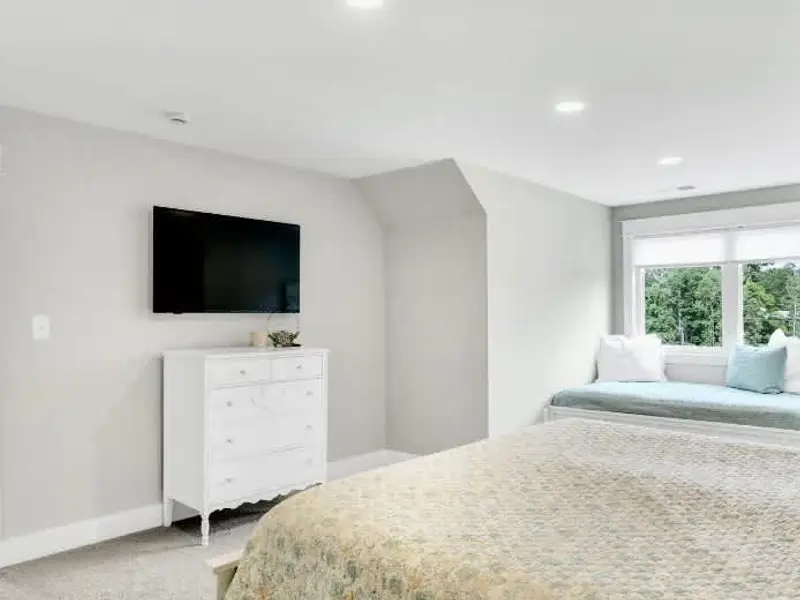 A Smart TV and antique dresser complete the space, blending modern comfort with timeless charm to create a warm, inviting retreat.
