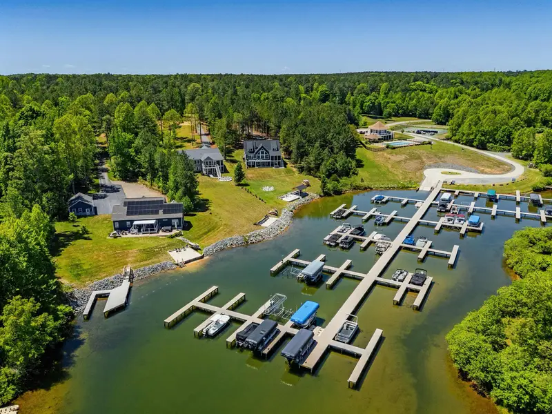 Marina Aerial - The Waters marina and covered slips spread along the cove, with the home tucked into the trees just above the water.