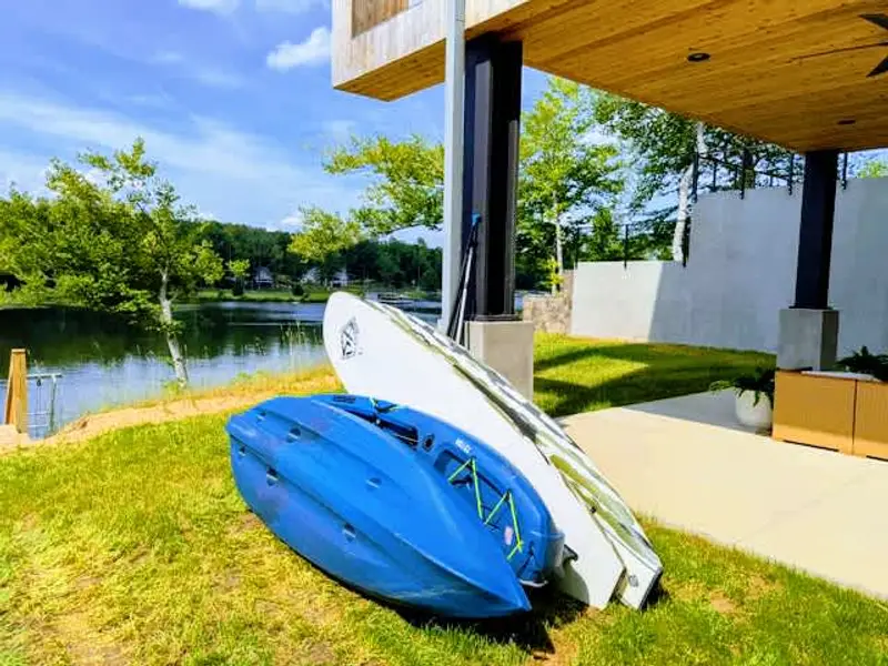 Water Toys - Two kayaks and two paddleboards staged by the lawn, ready for a morning paddle across the calm cove.