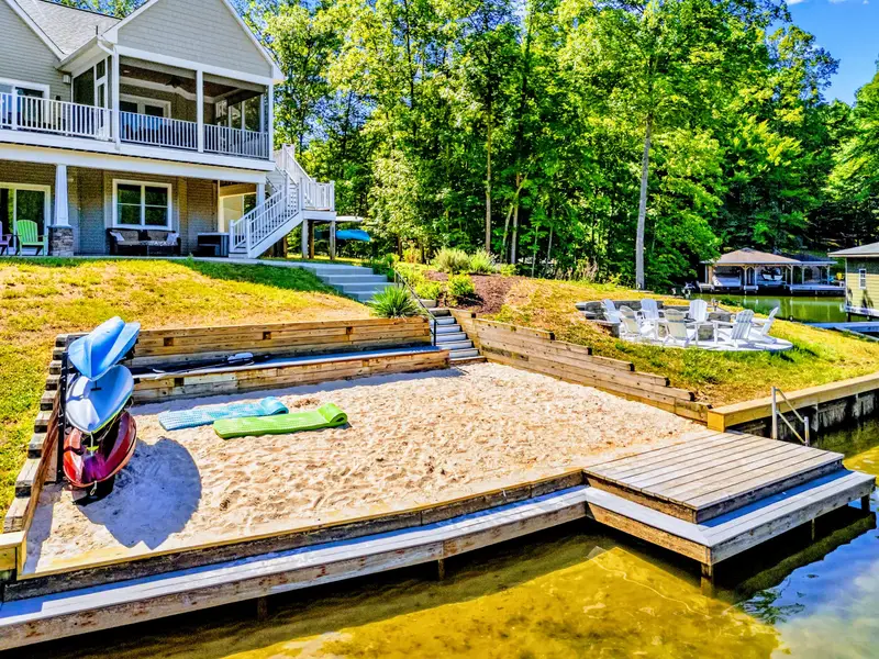 Sandy Beach - A rare flat, sandy shoreline with kayaks waiting at the water's edge and terraced lawn stepping down from the house.