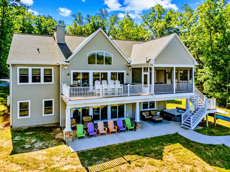 Rear Exterior - Layered decks, a screened porch, a hot tub, and a patio of colorful Adirondack chairs all face the lake.
