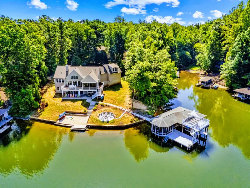 Aerial View - Wrapped in mature trees on the private side, the home, fire pit, and boathouse strung along the shoreline.