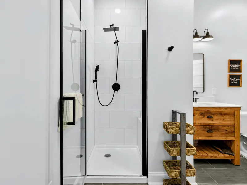 Bunk Bathroom - The walk-in glass shower is finished in clean white tile with a black rainfall and handheld setup, just steps from the vanity.