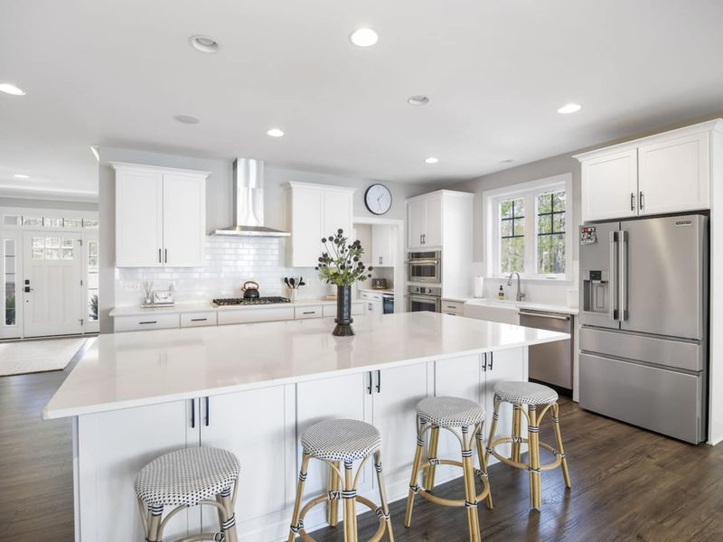 Large fully stocked kitchen with huge island, new stainless steel appliances, and large walk-in pantry.