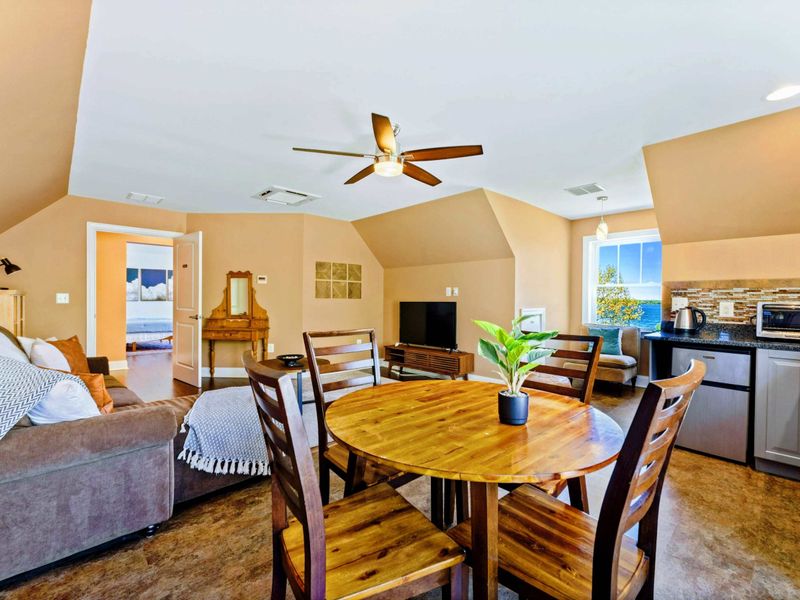 Large upper level primary suite with queen bed, balcony, fireplace, private TV area, and bathroom.