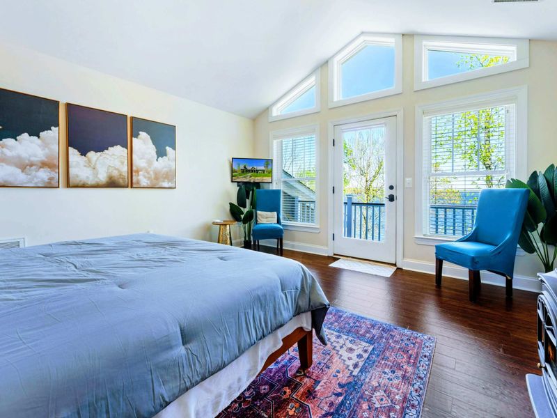 Large upper level primary suite with queen bed, balcony, fireplace, private TV area, and bathroom.