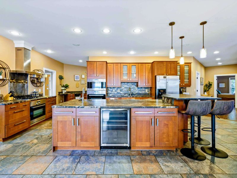 Large fully stocked main kitchen with huge island, and stainless steel appliances.