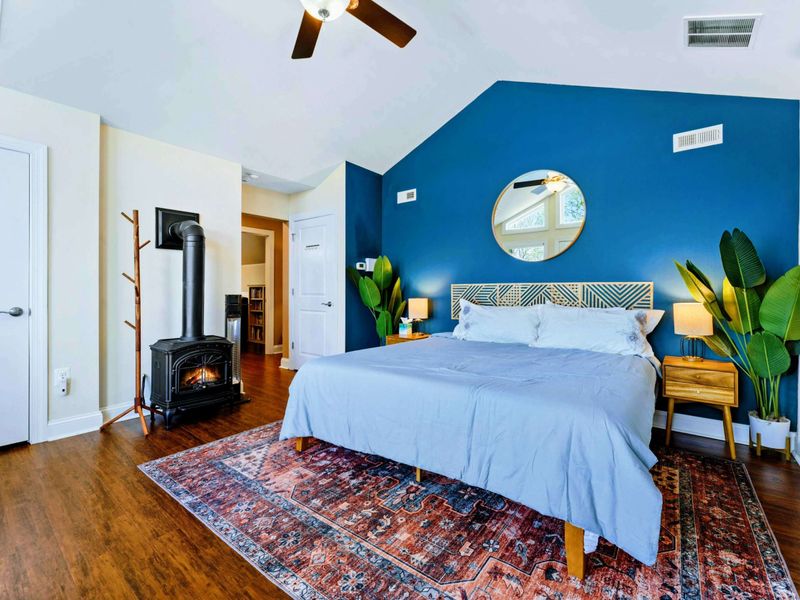 Large upper level primary suite with queen bed, balcony, fireplace, private TV area, and bathroom.