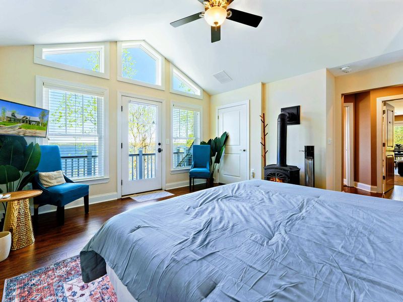 Large upper level primary suite with queen bed, balcony, fireplace, private TV area, and bathroom.