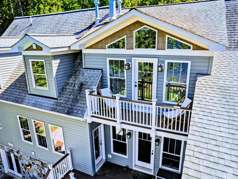 Large upper level primary suite with queen bed, balcony, fireplace, private TV area, and bathroom.