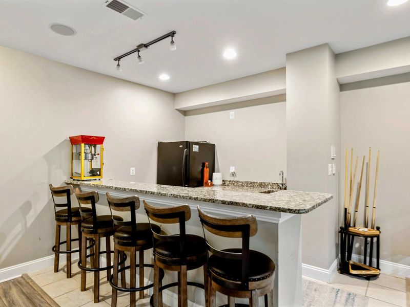 Game Room Bar - A granite-top bar with stools, popcorn machine, and fridge, right off the game room for easy refills.