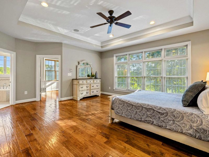 Ensuite 2 - Hardwood floors, a dresser, and an open doorway to the ensuite bath with the tub just visible.