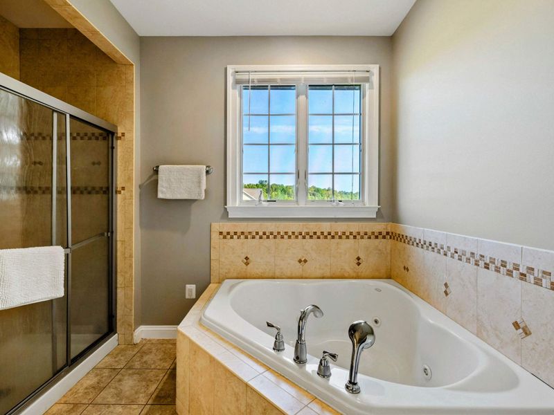 Ensuite 2 Bath - Closer view of the jacuzzi tub and walk-in shower with decorative tile banding.
