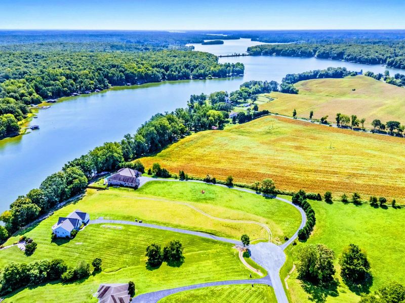 Aerial - A wider view showing the property's position on the lake, with farmland and water stretching to the horizon.