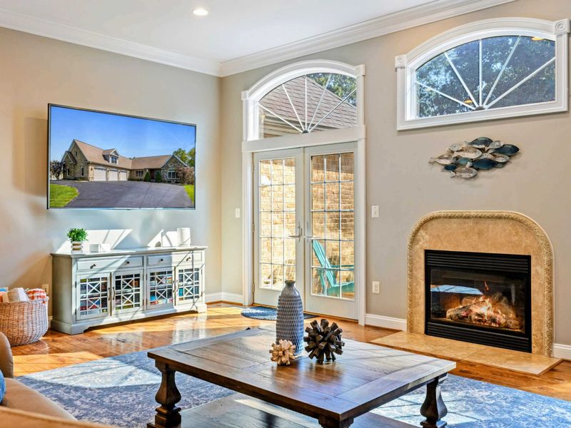 Living Room - Arched windows and a stone fireplace frame this elegant room, with a large Smart TV and plush seating.