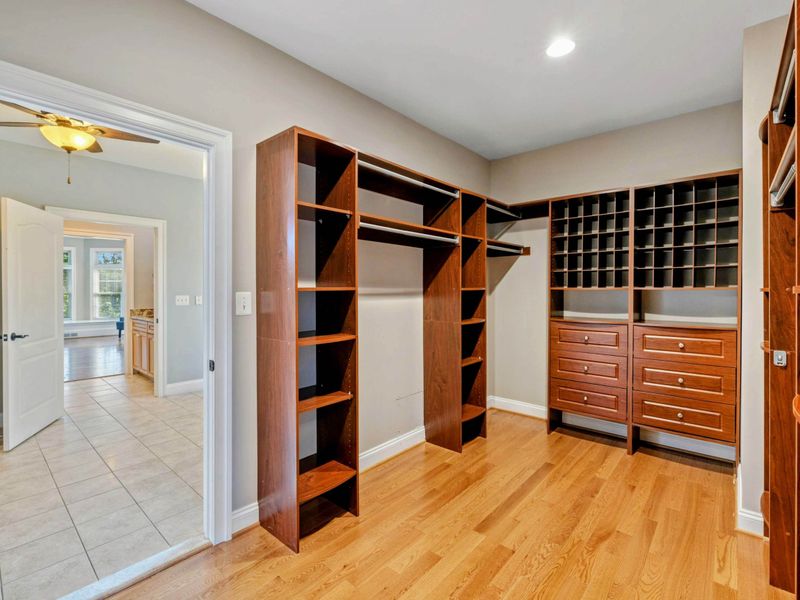 Primary Suite - A custom walk-in closet with built-in cherry shelving, drawers, and shoe cubbies.