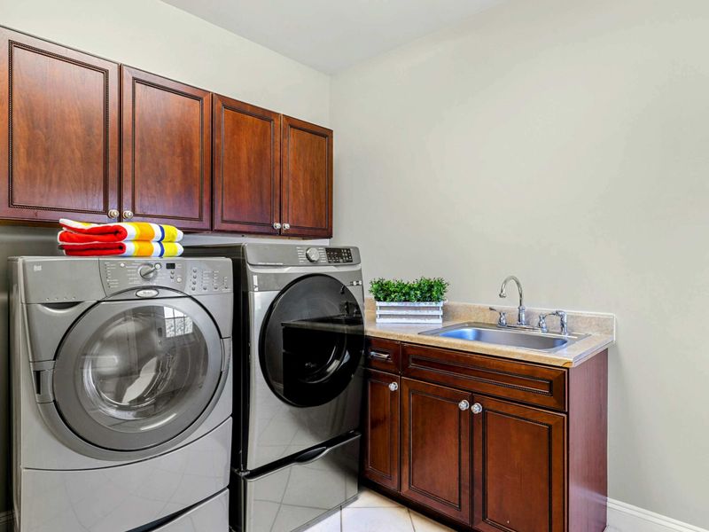 Laundry Room - Full-size front-load washer and dryer with a utility sink and overhead cabinets.